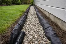 Drainage solutions in Orangevale CA by McGuire Earth Works - French drain installation with gravel-filled trench along home foundation